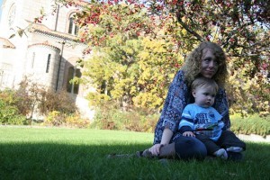 Maggie and her godson sitting in the grass on a college campus.