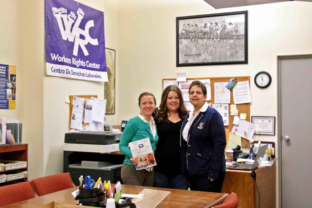 Photograph of three women in an office with a Workers Rights Center flag in the background.