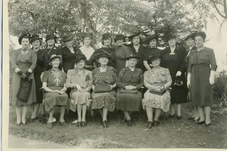 Old photograph of women dressed in victorian clothing, posing in two rows..
