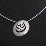 Photograph of the pendent necklace representing women supporting women.