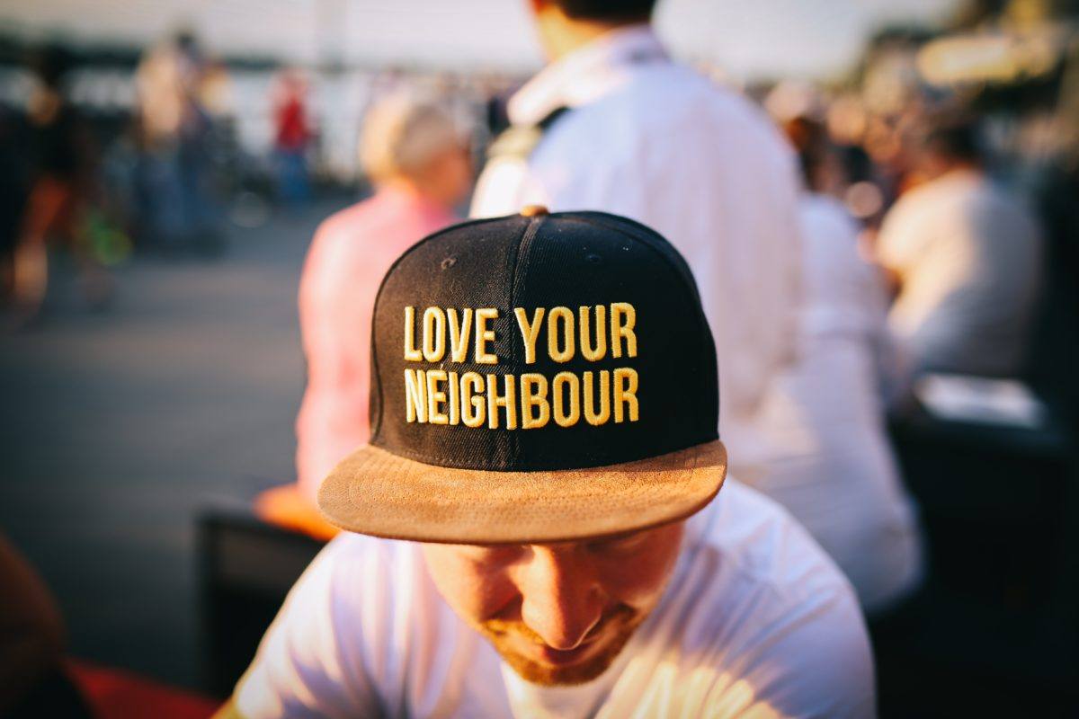 Photograph of a man wearing a hat that says "love your neighbor"