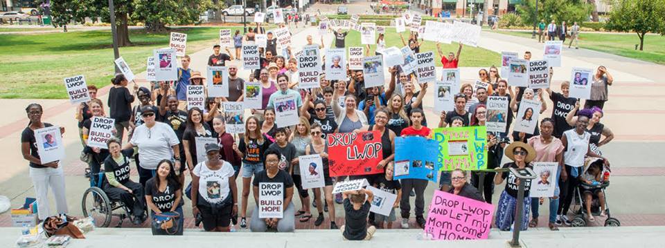 Large group of people holding signs that read DROP LWOP and other slogans.