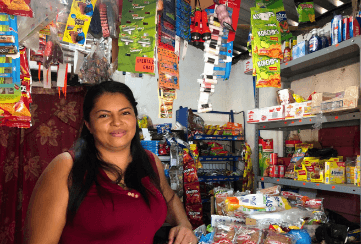 Mirna Lopez stands in the tienda she owns where she sells basic food.