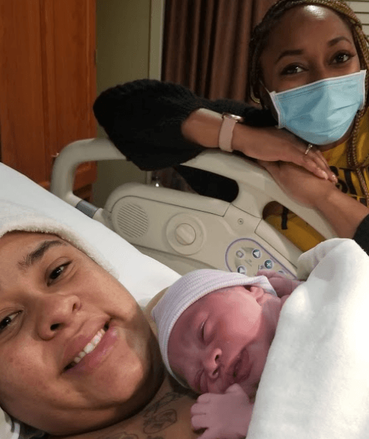 Mother pictured with newborn baby and doula.