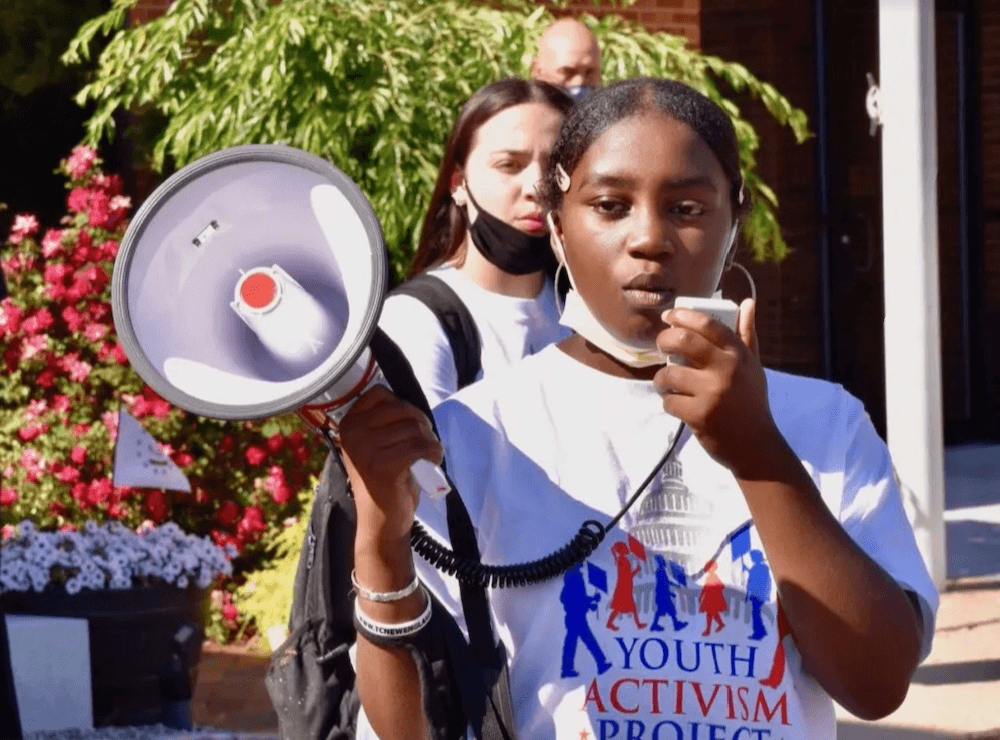 Young woman using megaphone at protest with Mary's Pence Grantee Youth Activism Project